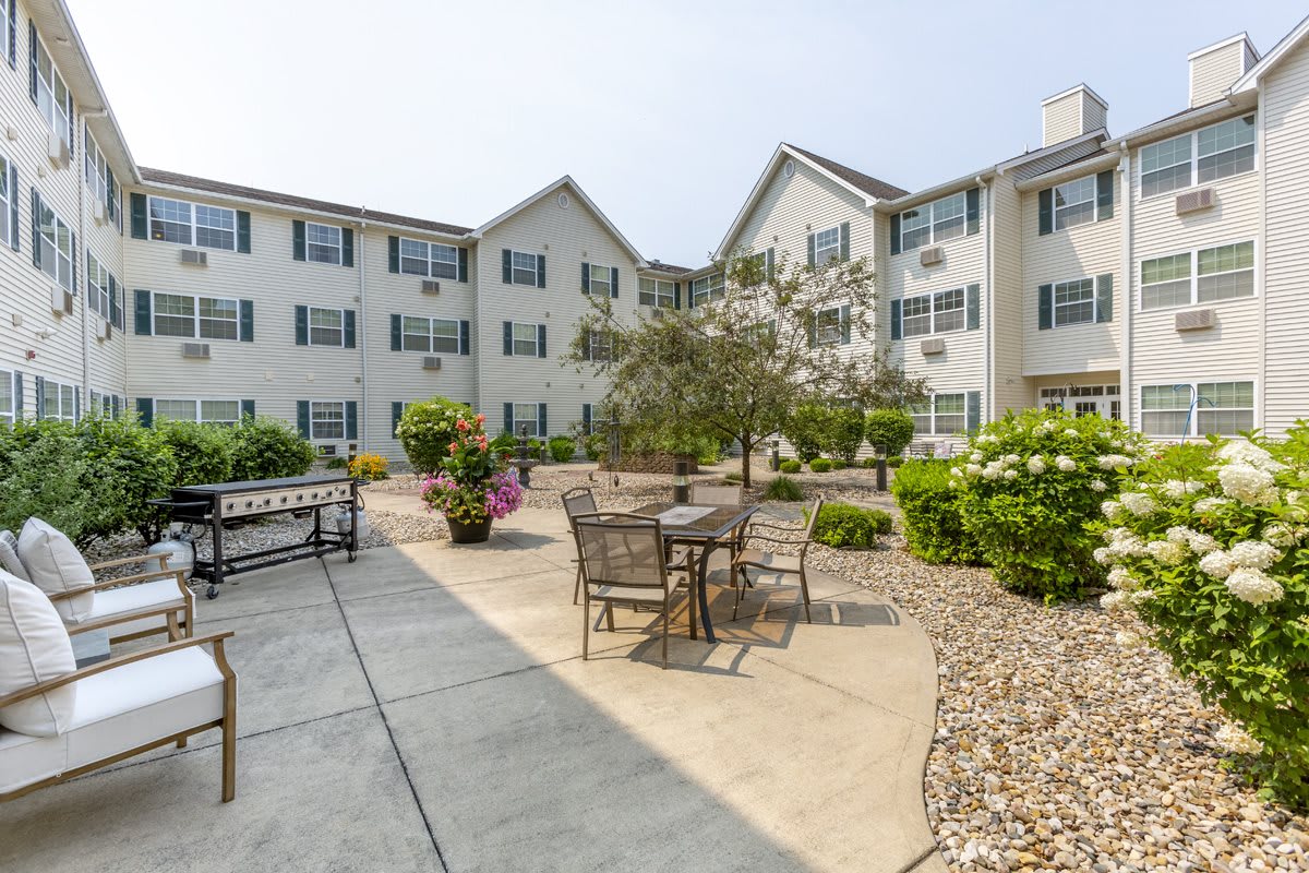 A serene courtyard with outdoor seating surrounded by greenery and a multi-story building.
