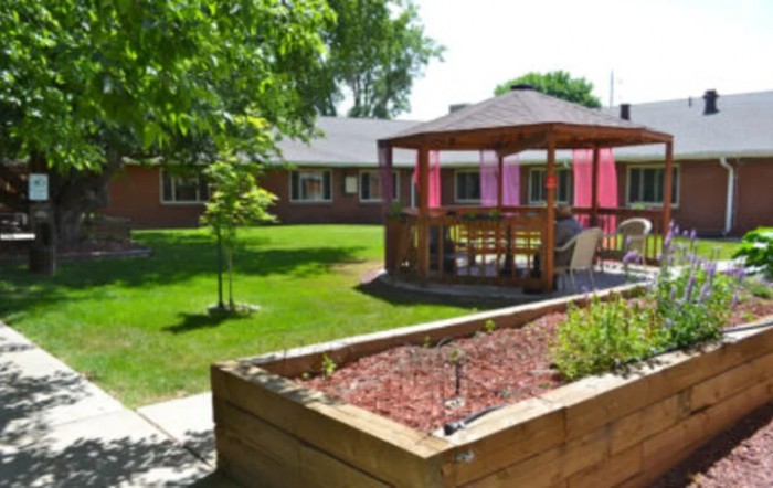 A serene garden area featuring a wooden gazebo and well-maintained landscaping.