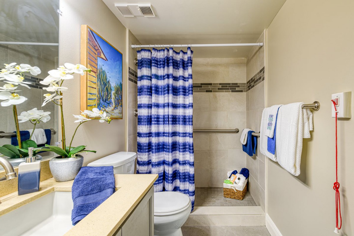 A neatly designed bathroom featuring a blue and white shower curtain, complemented by matching towels and a potted plant.