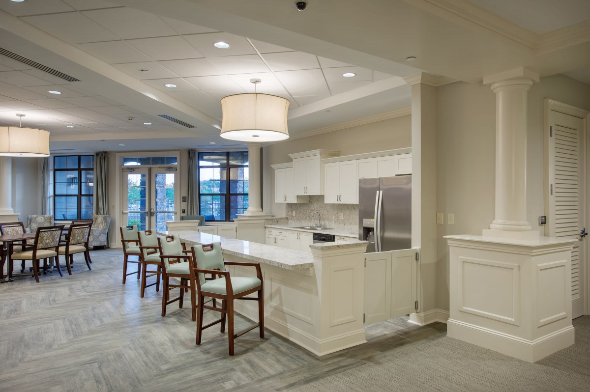 A modern kitchen with an island counter and wooden bar stools, featuring sleek white cabinetry and a cozy atmosphere.