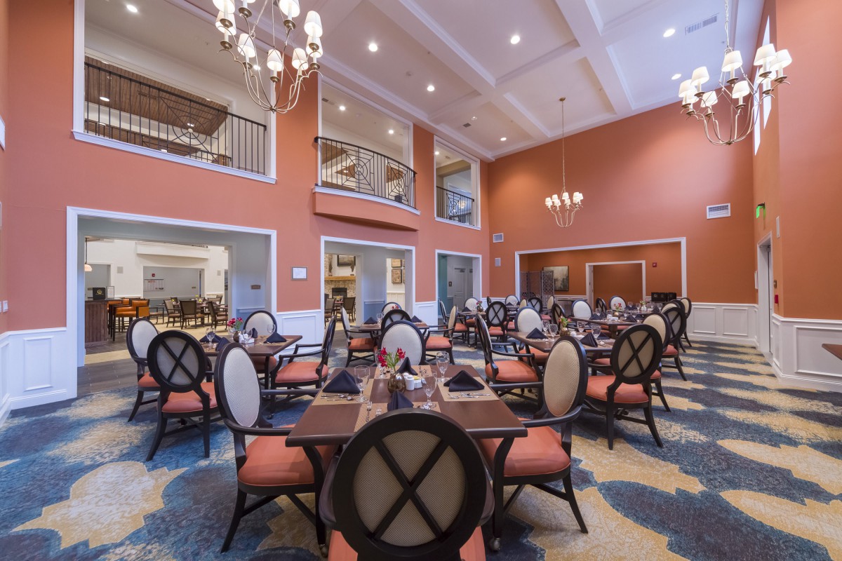 An elegant and spacious dining room with arranged tables and chandeliers.