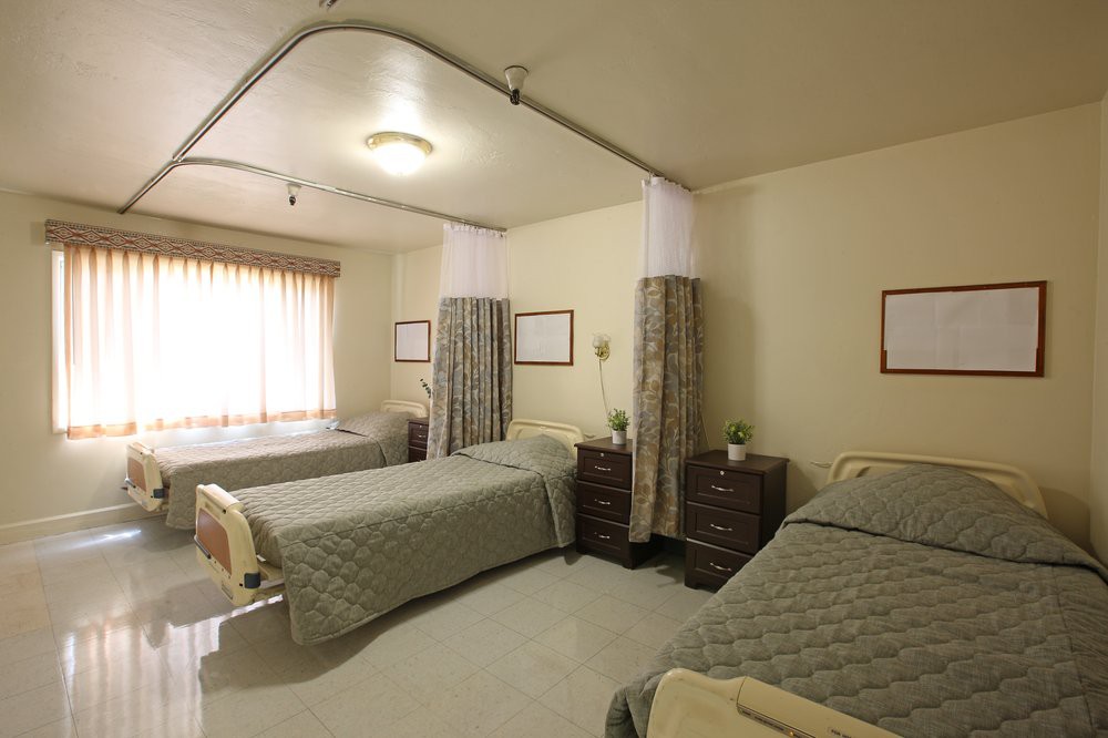 A hospital room with two beds and privacy curtains.