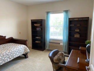 A cozy bedroom with a bed, two bookshelves, and a desk by the window.