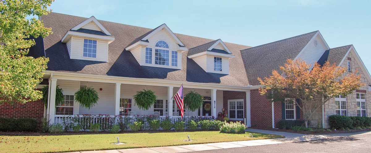 A charming suburban house with a porch and American flag in the yard.