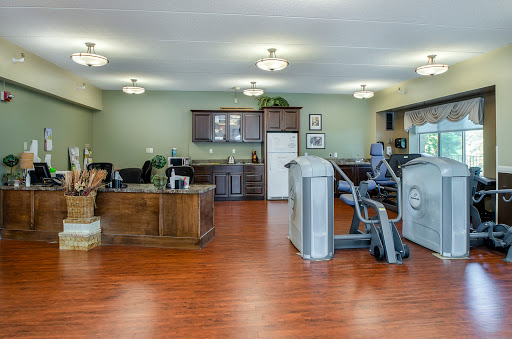 A spacious and well-lit fitness room featuring exercise equipment and a kitchenette.