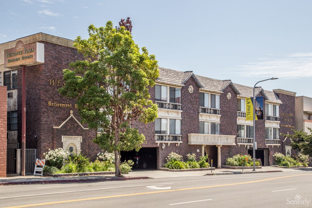 A view of a residential building along a city street with trees lining the sidewalk.