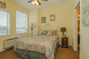 Cozy bedroom with a bed, bedside tables, and a lamp near a window.