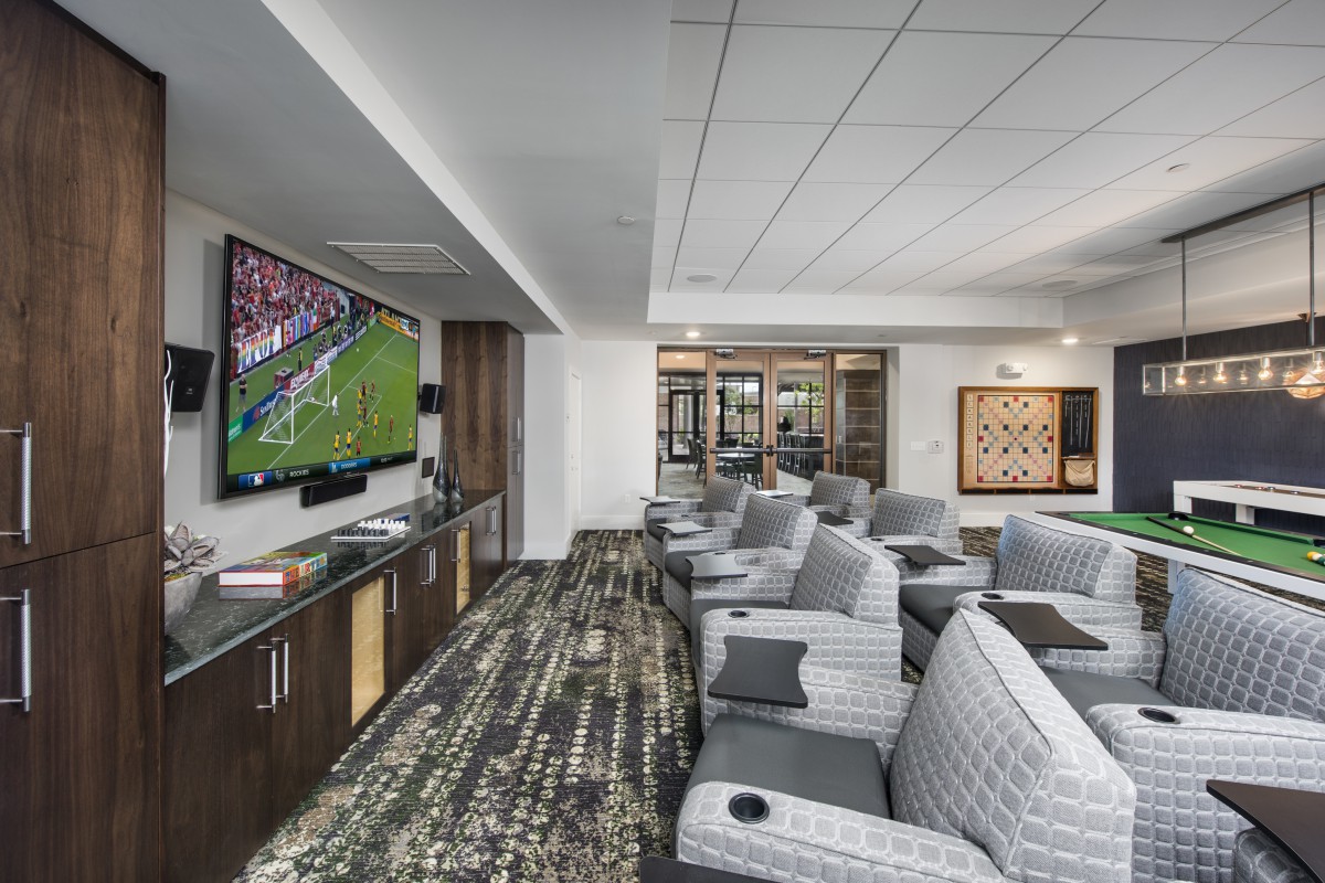A luxurious lounge area with comfortable seating and a large TV displaying a sports game.