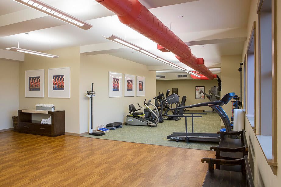 A well-equipped gym with exercise machines and treadmills in a clean, bright setting.