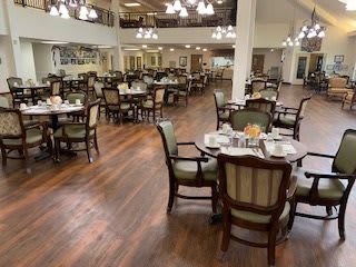 A spacious dining room with elegant tables and chairs, illuminated by chandeliers.