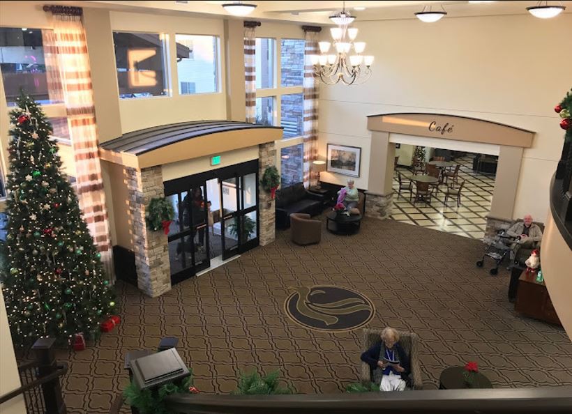 A hotel lobby featuring a decorated Christmas tree, seating area, and chandelier.