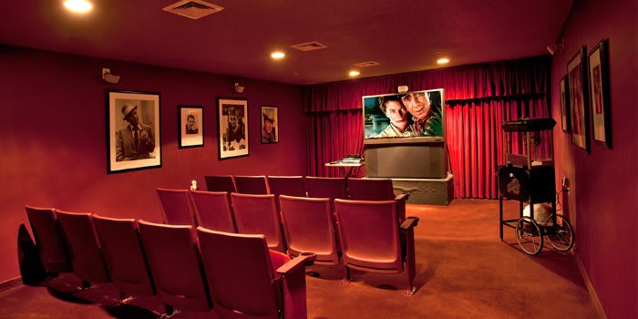 A cozy home theater with red seating and movie posters on the walls.
