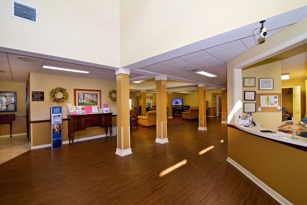 A spacious lobby with wooden flooring, reception desk, and comfortable seating areas.