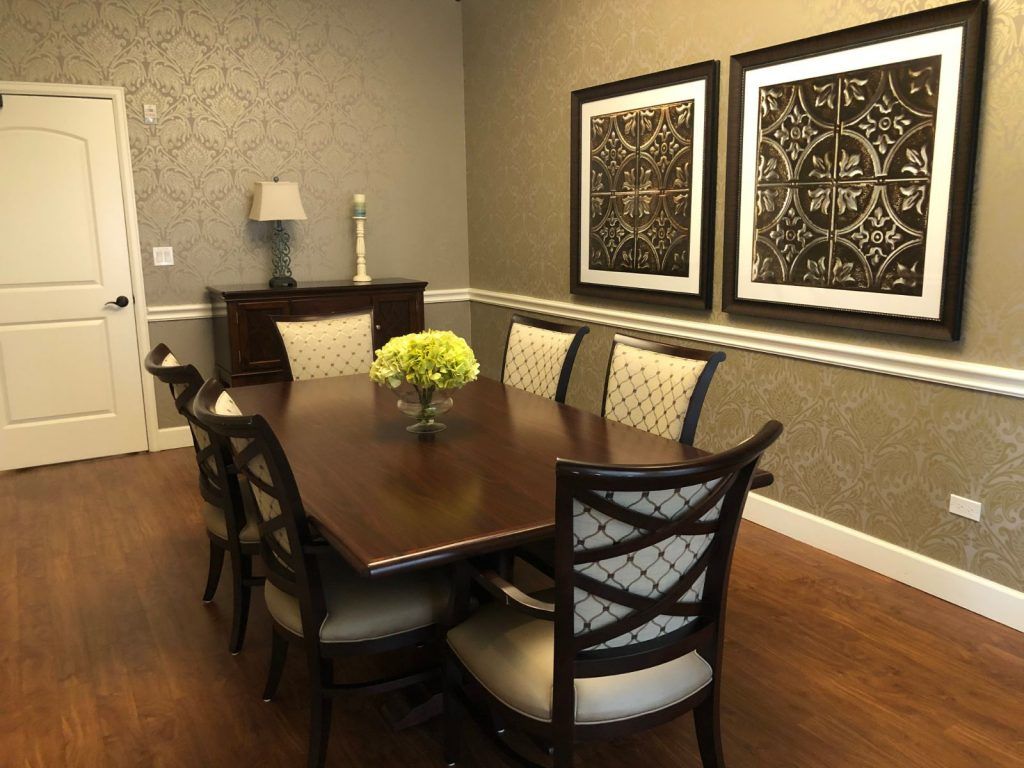 A neatly arranged dining room featuring a wooden table, cushioned chairs, and decorative artwork on the walls.