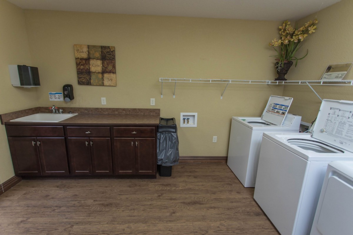 A tidy laundry room with a washer, dryer, and storage cabinets.