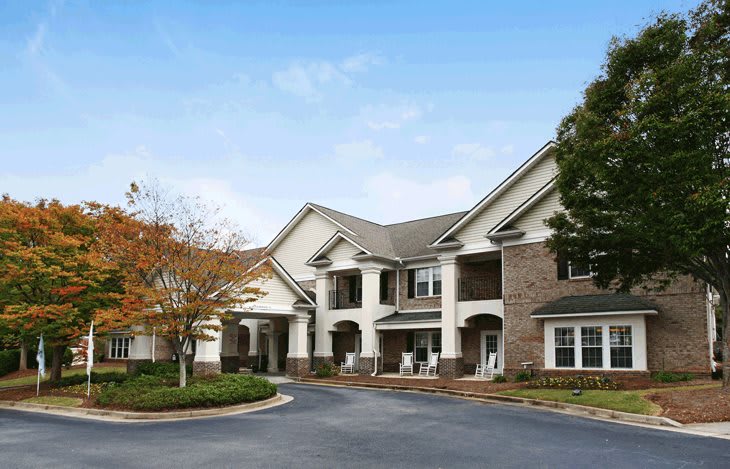 A residential building with a landscaped exterior and trees in the foreground.