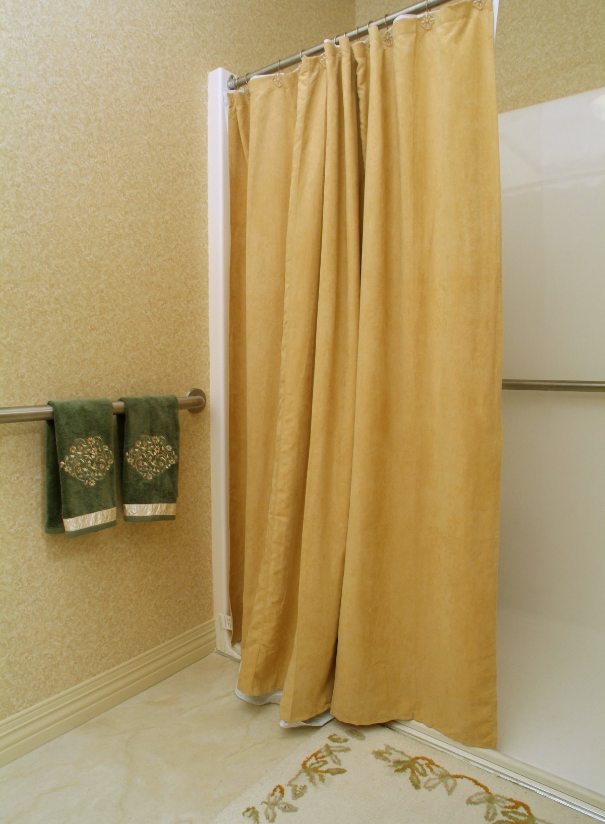 A bathroom with a yellow shower curtain and green towels.