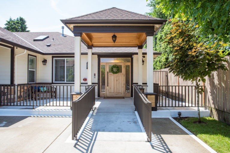 A residential entrance featuring a ramp and columns leading to the front door.