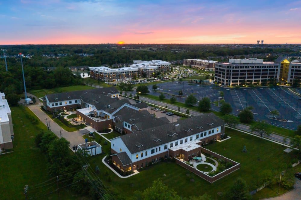Aerial view of an office park at sunset, featuring multiple buildings surrounded by greenery.