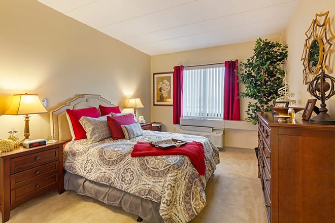 A cozy bedroom with patterned bedding and bold red accents.