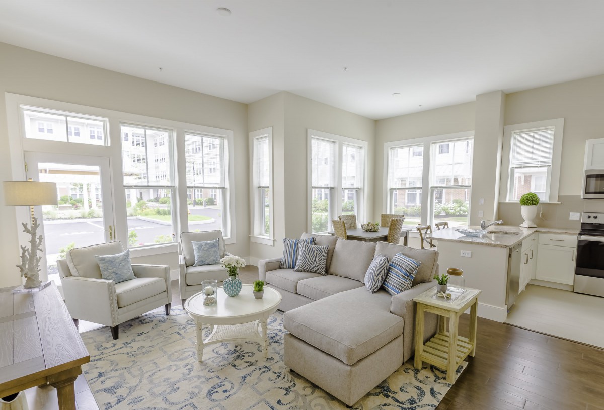 A bright and modern living room with large windows and light-colored furniture.