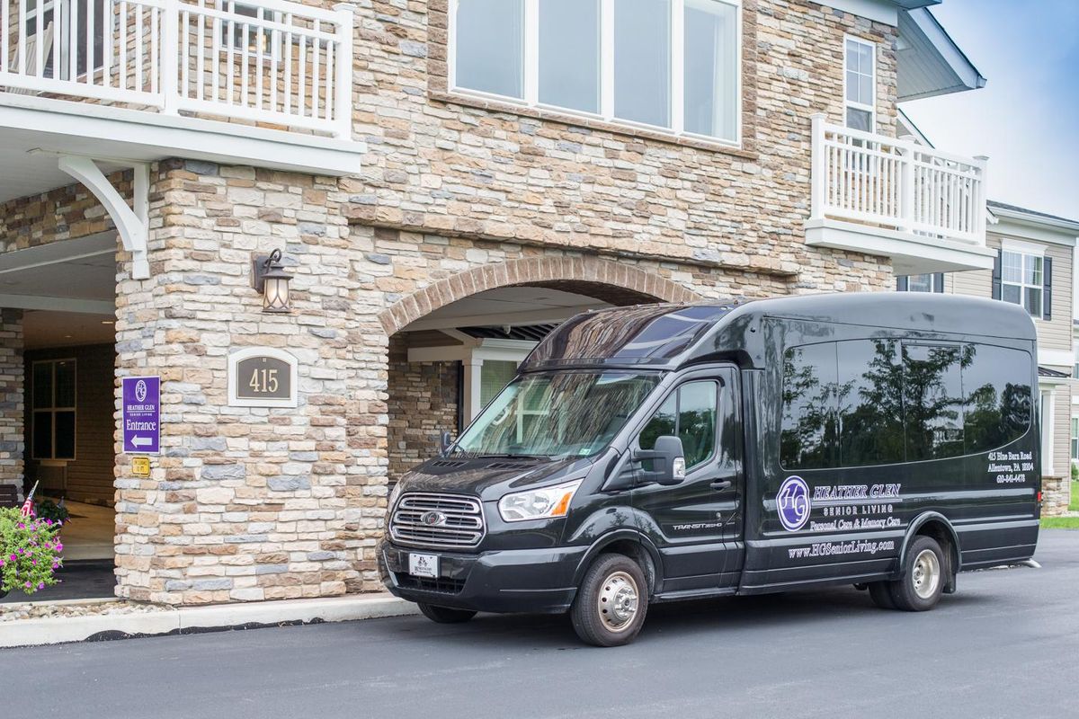 A black van parked in front of a building with a brick exterior.