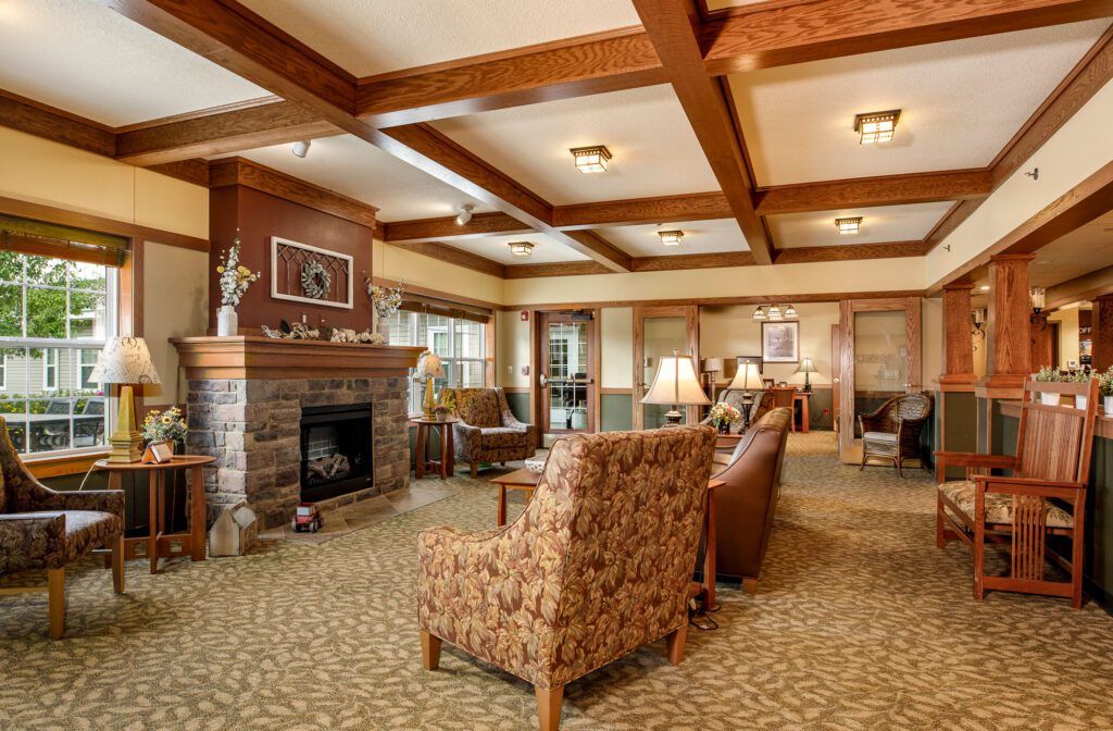 A cozy living room with a fireplace and comfortable seating, featuring wooden beams and a carpeted floor.