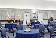 An elegantly decorated dining area featuring round tables with blue tablecloths and classic chairs.