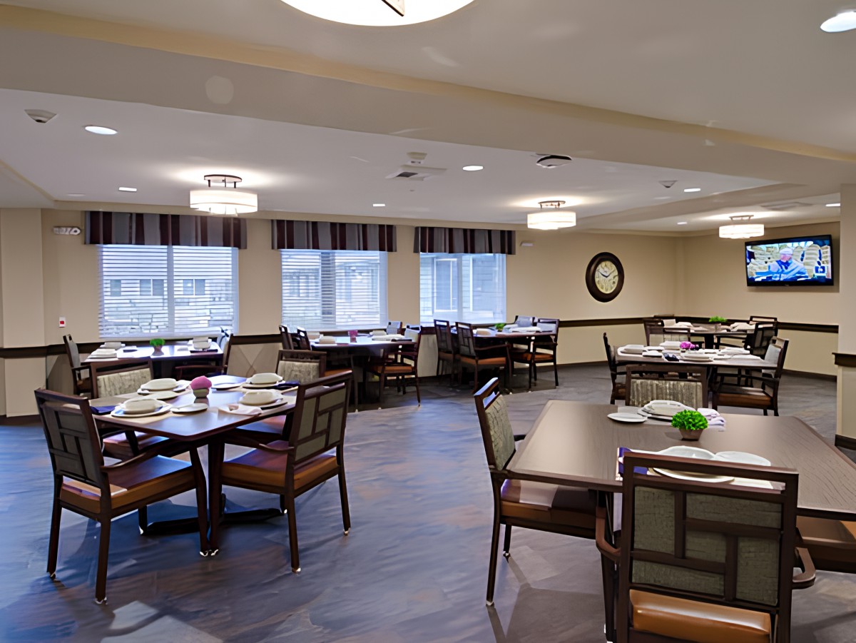 A neatly arranged dining area with tables and chairs, featuring modern lighting and large windows.
