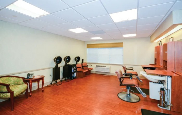 An empty hair salon with chairs, hair dryers, and wooden flooring.