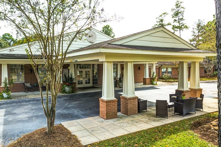 A welcoming building entrance with columns and a small outdoor seating area.