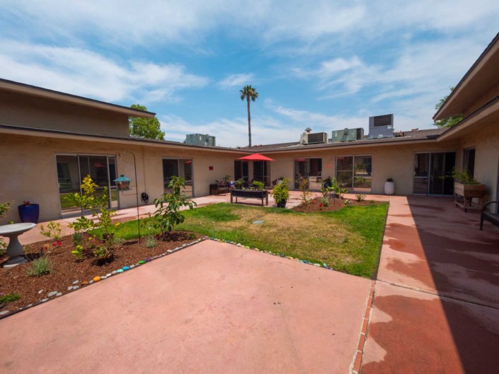 A courtyard with landscaped gardens and a central patio area in an apartment complex.