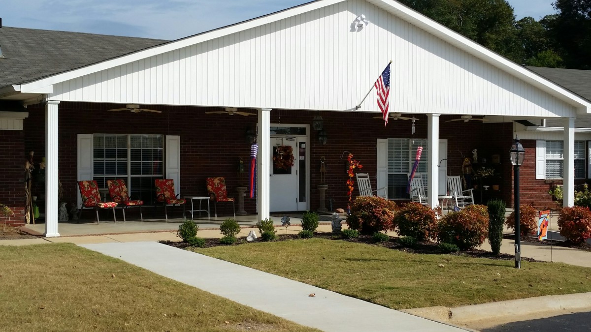 A charming house with a front porch decorated for the season, featuring an American flag and colorful plants.