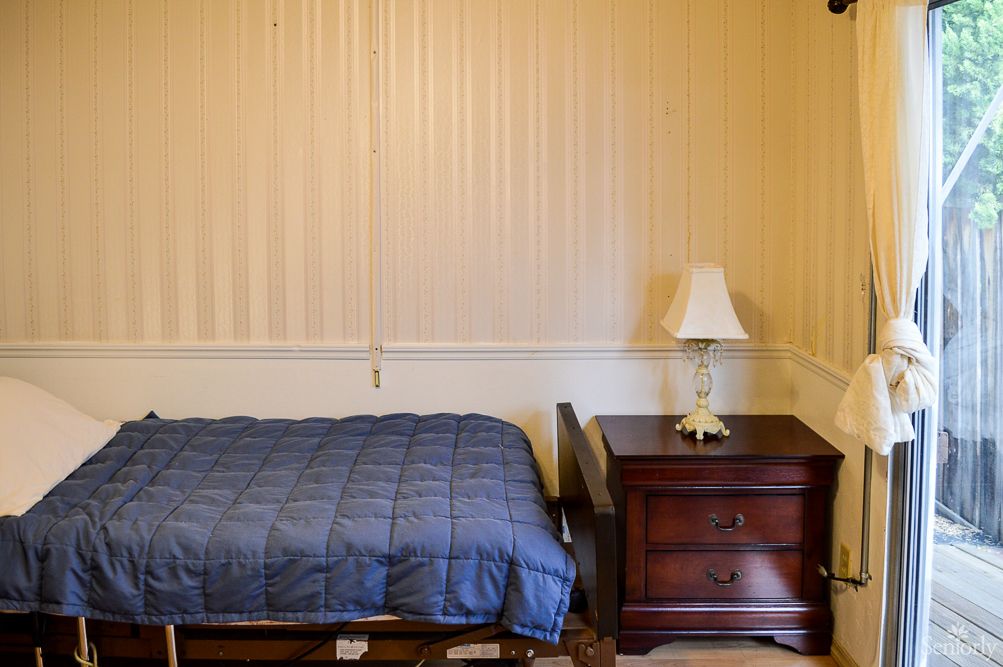 A simple bedroom with a bed, nightstand, and lamp.