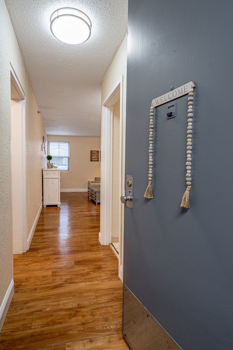 A welcoming hallway with wooden floors and a decorated door.