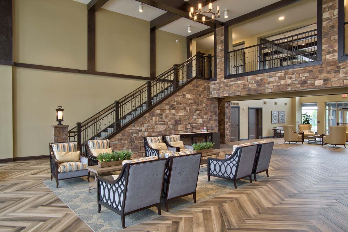 A stylish lobby with comfortable seating, brick accents, and a grand staircase.