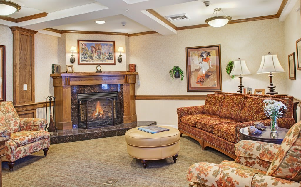 A cozy living room with a fireplace, sofa, and artwork on the walls.