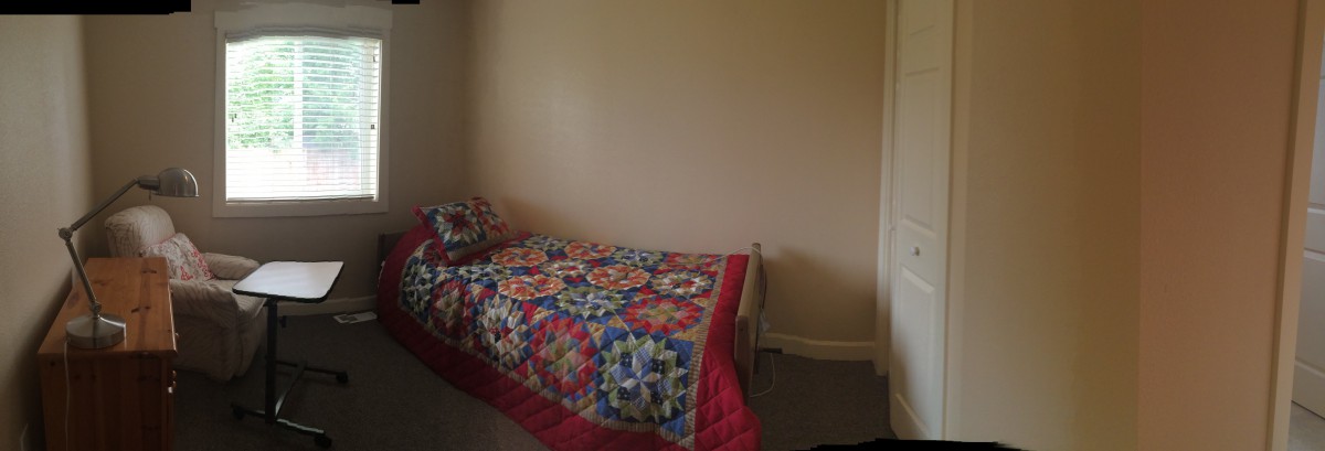 A simple bedroom with a single bed covered by a colorful quilt.
