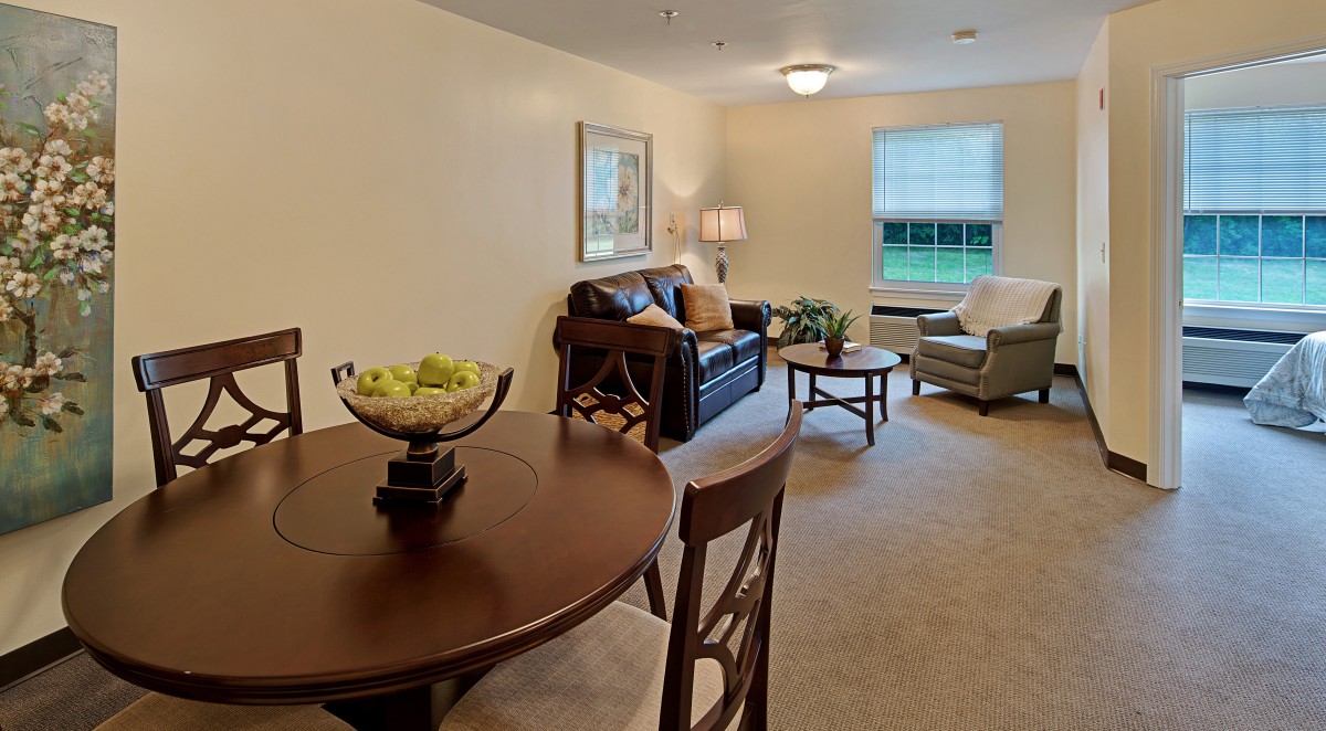 A cozy living room with a sofa, coffee table, and dining area.
