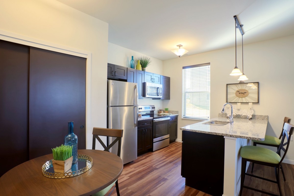 Modern kitchen with stainless steel appliances and wood flooring.