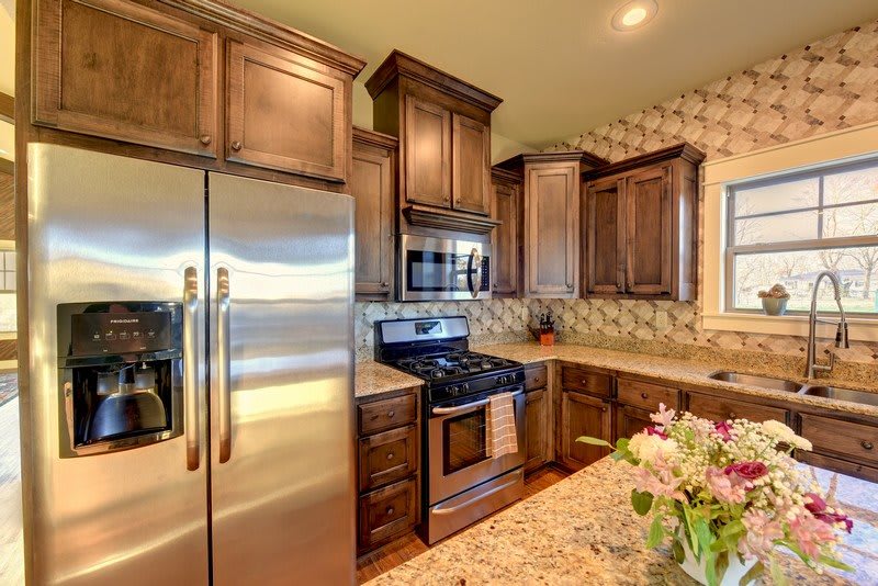 A modern kitchen featuring wooden cabinets, stainless steel appliances, and a decorative tile backsplash.