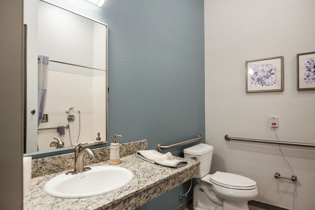 A modern bathroom with a granite countertop and blue accent wall.