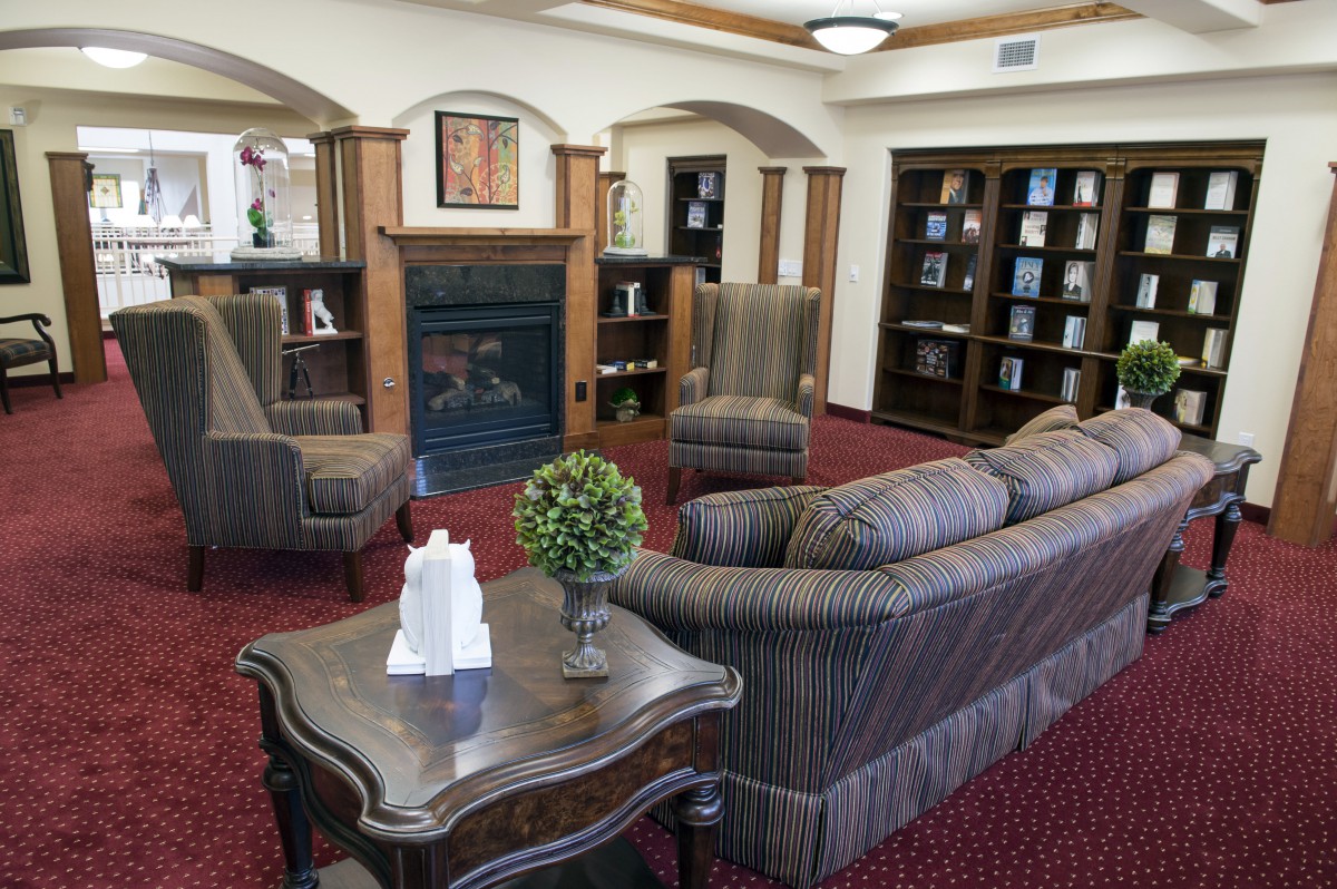 A cozy living room with sofas, chairs, a fireplace, and bookshelves.