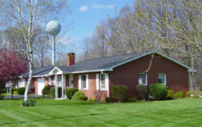 A brick house with a well-maintained lawn and a water tower in the background.