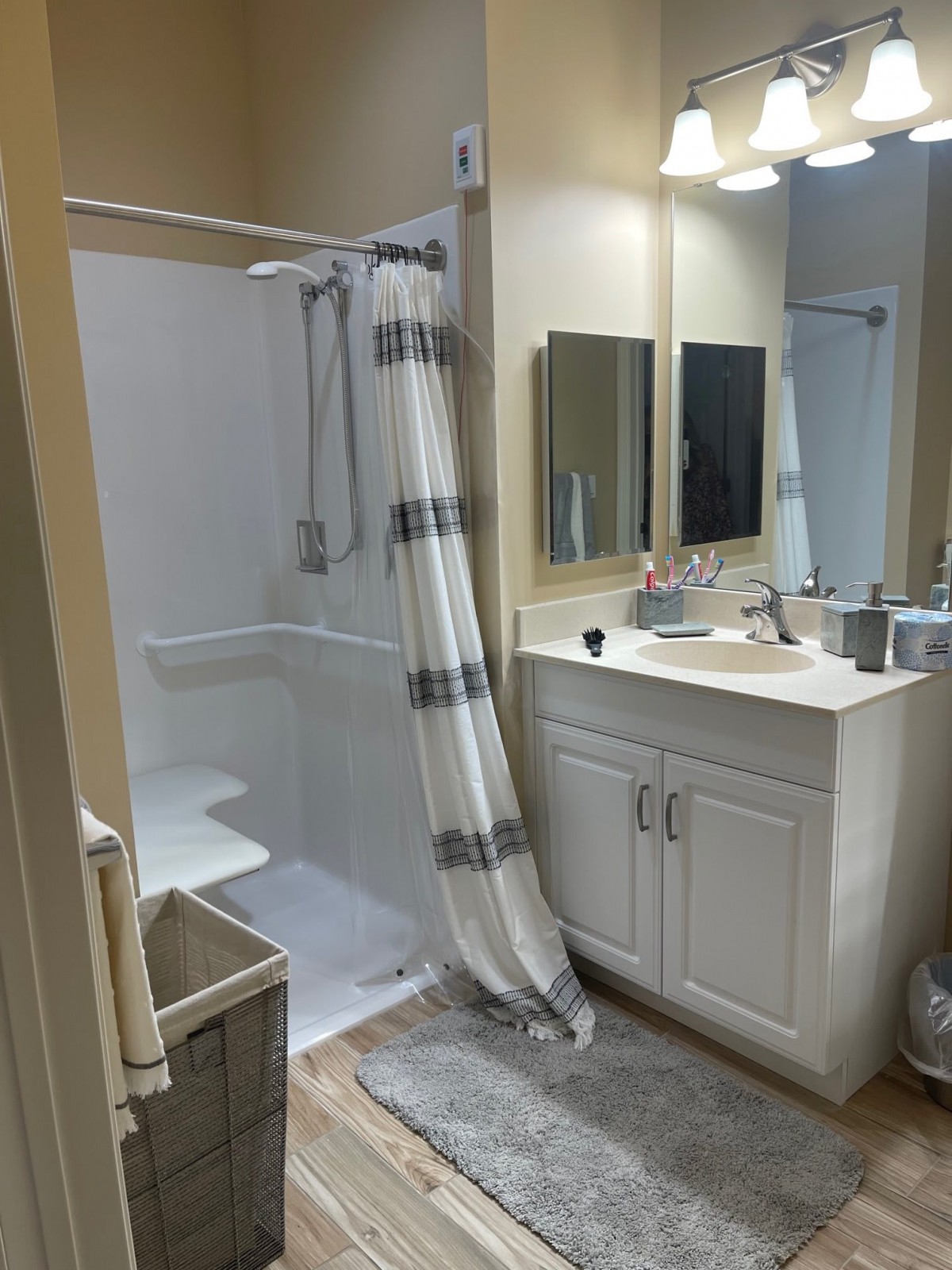 A clean and organized bathroom featuring a shower with a curtain, a vanity with a sink and mirror, and neatly arranged towels.