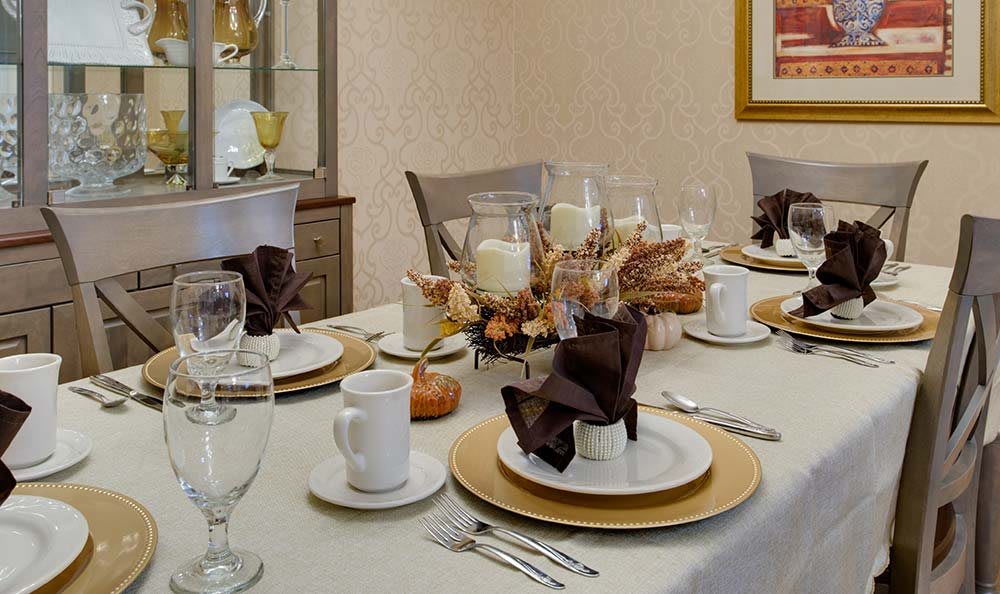 An elegantly set dining table with candles and a centerpiece.