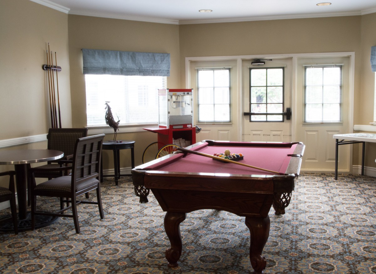 A cozy game room featuring a red pool table and popcorn machine.