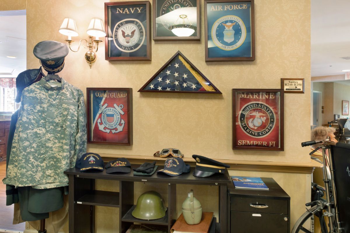 A display of military memorabilia including uniforms, flags, and emblems from various branches such as the Navy, Air Force, Army, and Marines.