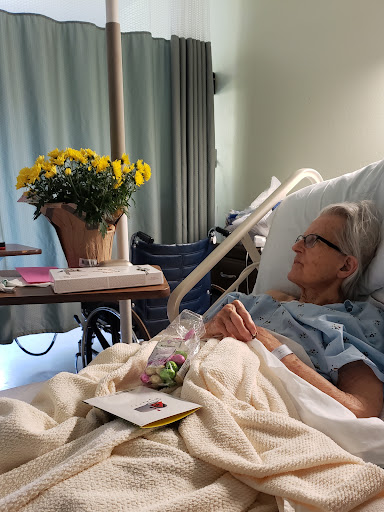 A patient resting in a hospital bed, accompanied by cheerful flowers and personal items.