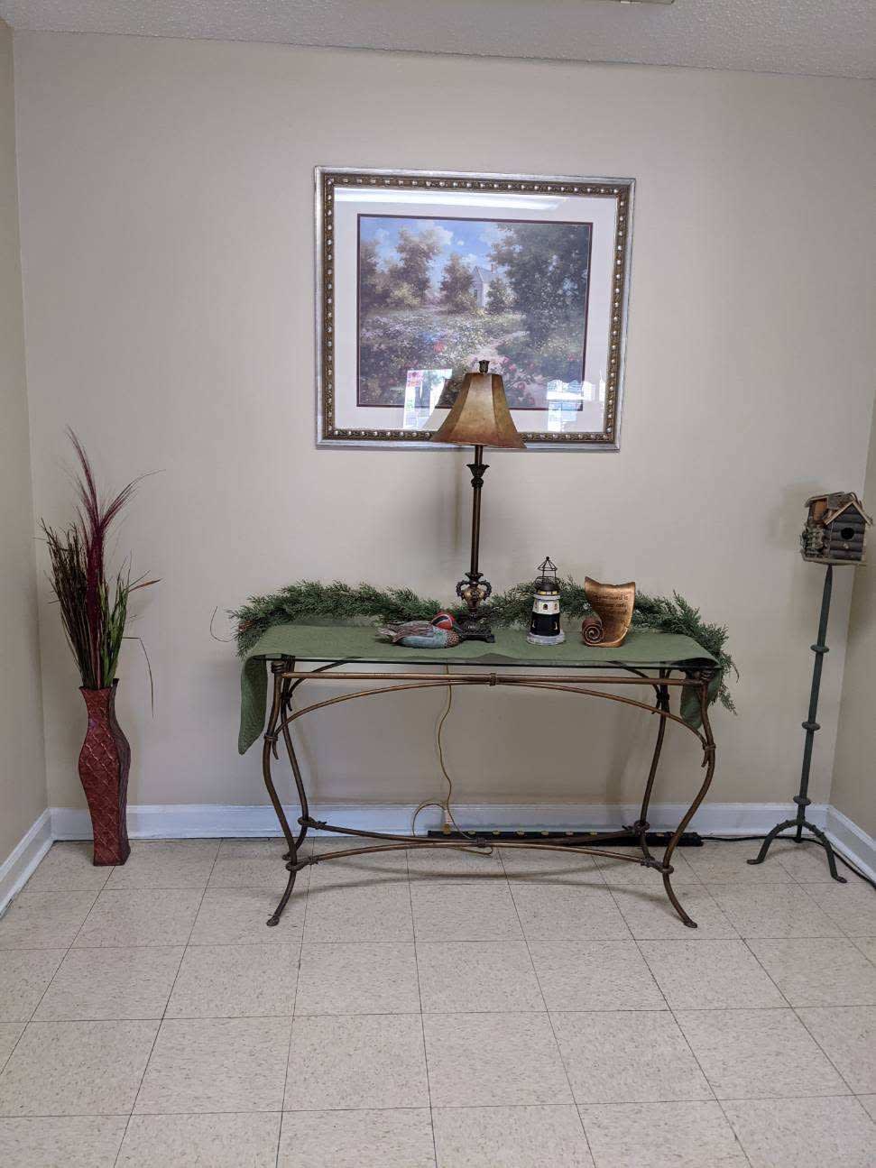A decorated hallway corner with a table, lamp, and wall art.